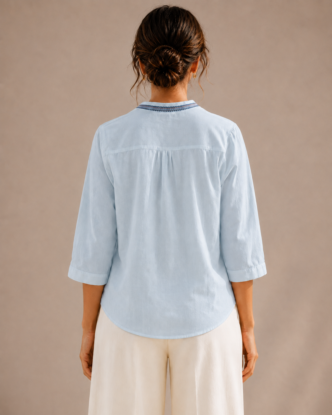 Back view of the untucked sky blue medallion embroidered cotton shirt, showing the curved hem and relaxed fit.
