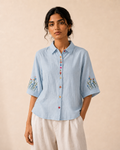 Woman wearing the sky blue wildflower embroidered cotton shirt, front view.
