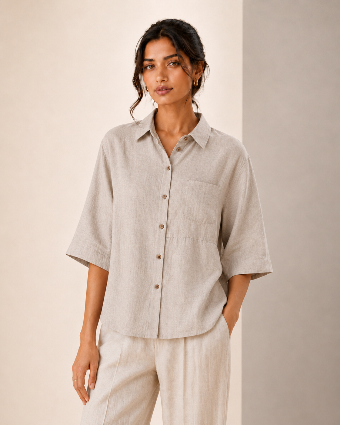 Studio front view of the stone grey back embroidered embroidered linen shirt styled with light trousers.
