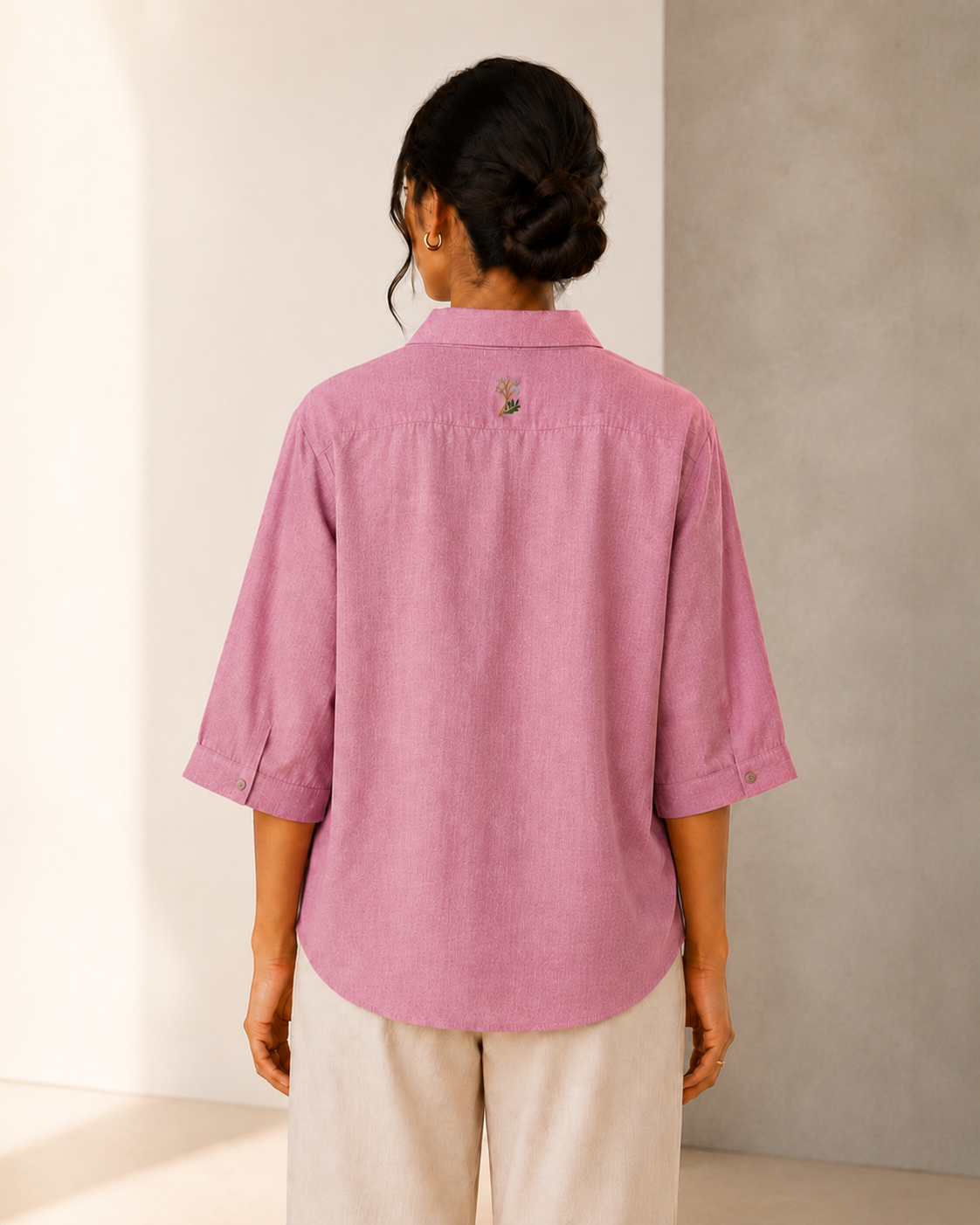 Back view of the soft blush pink back embroidered embroidered linen shirt, showing the rear yoke and relaxed fit.

