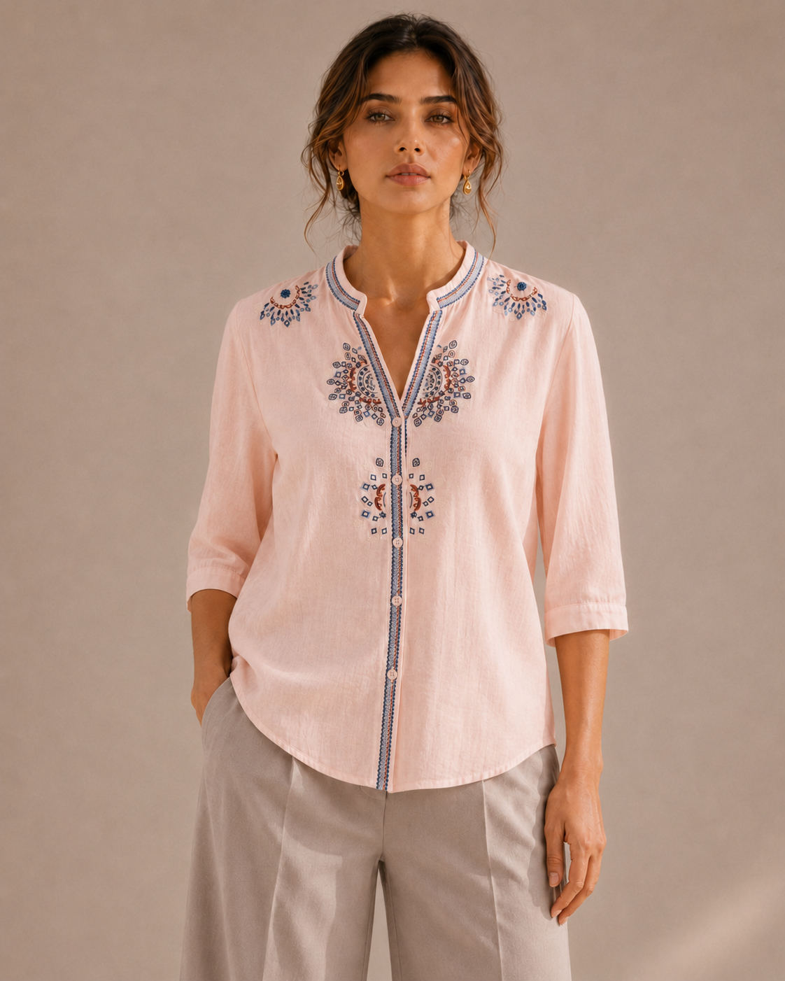 Front view of the untucked soft blush pink medallion embroidered cotton shirt, showing the full embroidery placement and curved hem.
