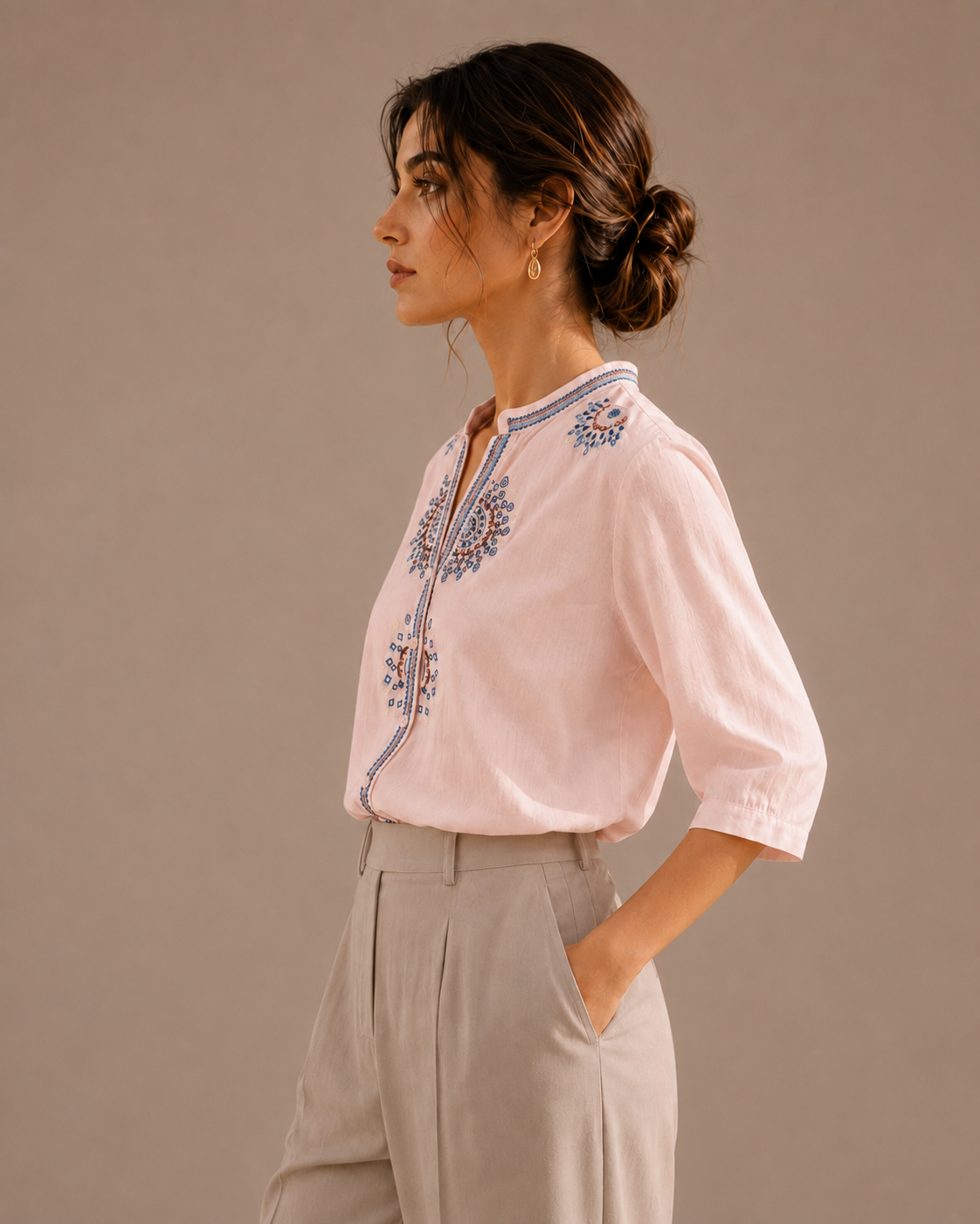 Side profile of a woman wearing the soft blush pink medallion embroidered cotton shirt, showing the silhouette and embroidery.
