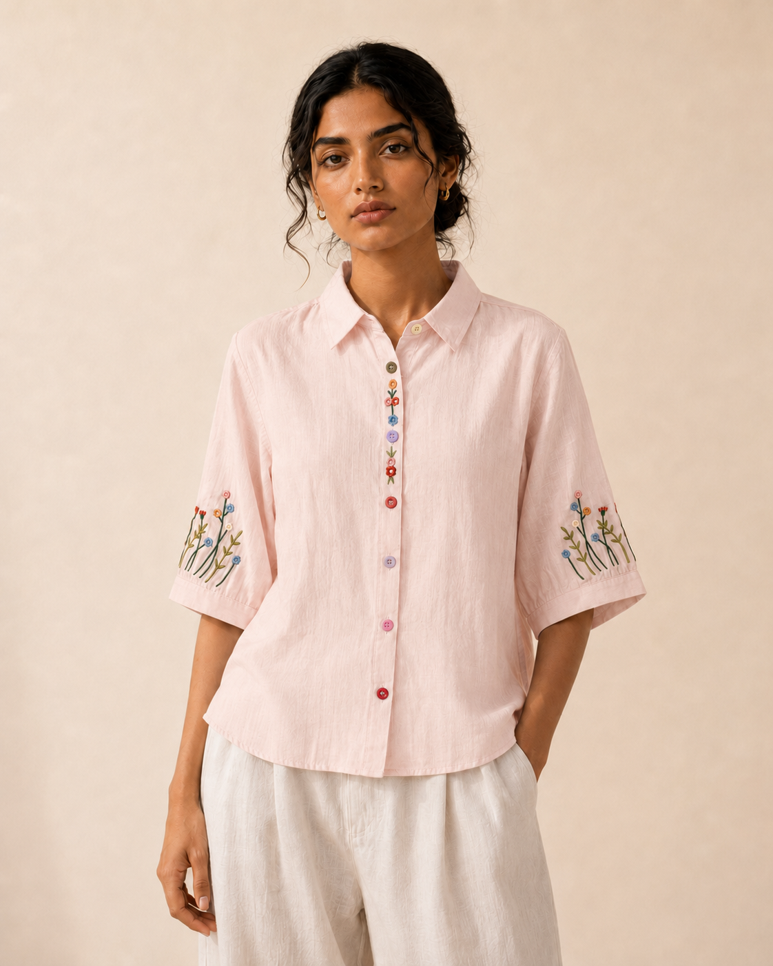 Woman wearing the soft blush pink wildflower embroidered cotton shirt, front view.

