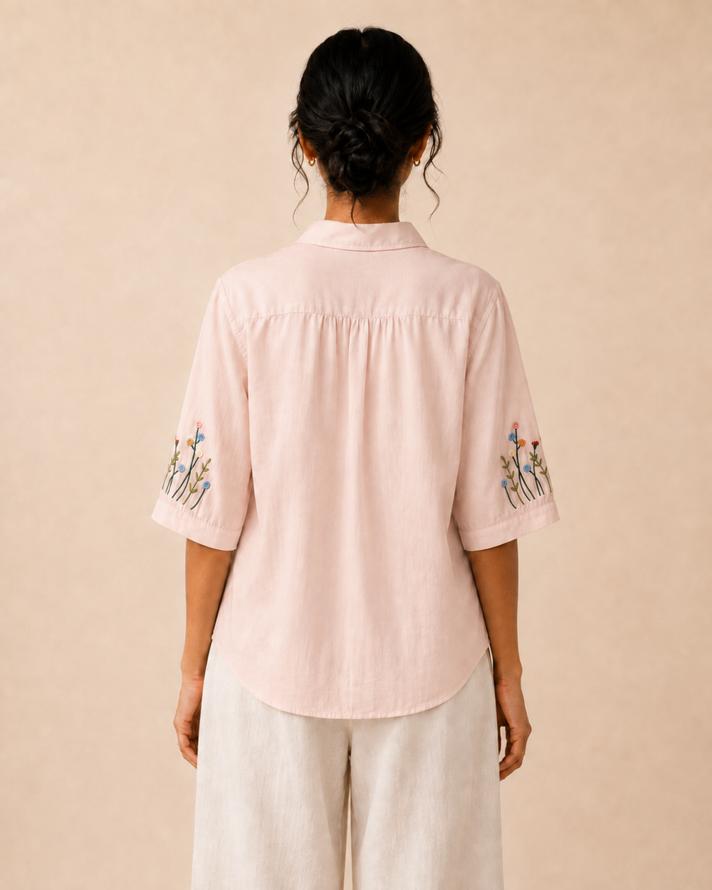 Back view of the soft blush pink wildflower embroidered cotton shirt, showing the rear yoke and relaxed fit.
