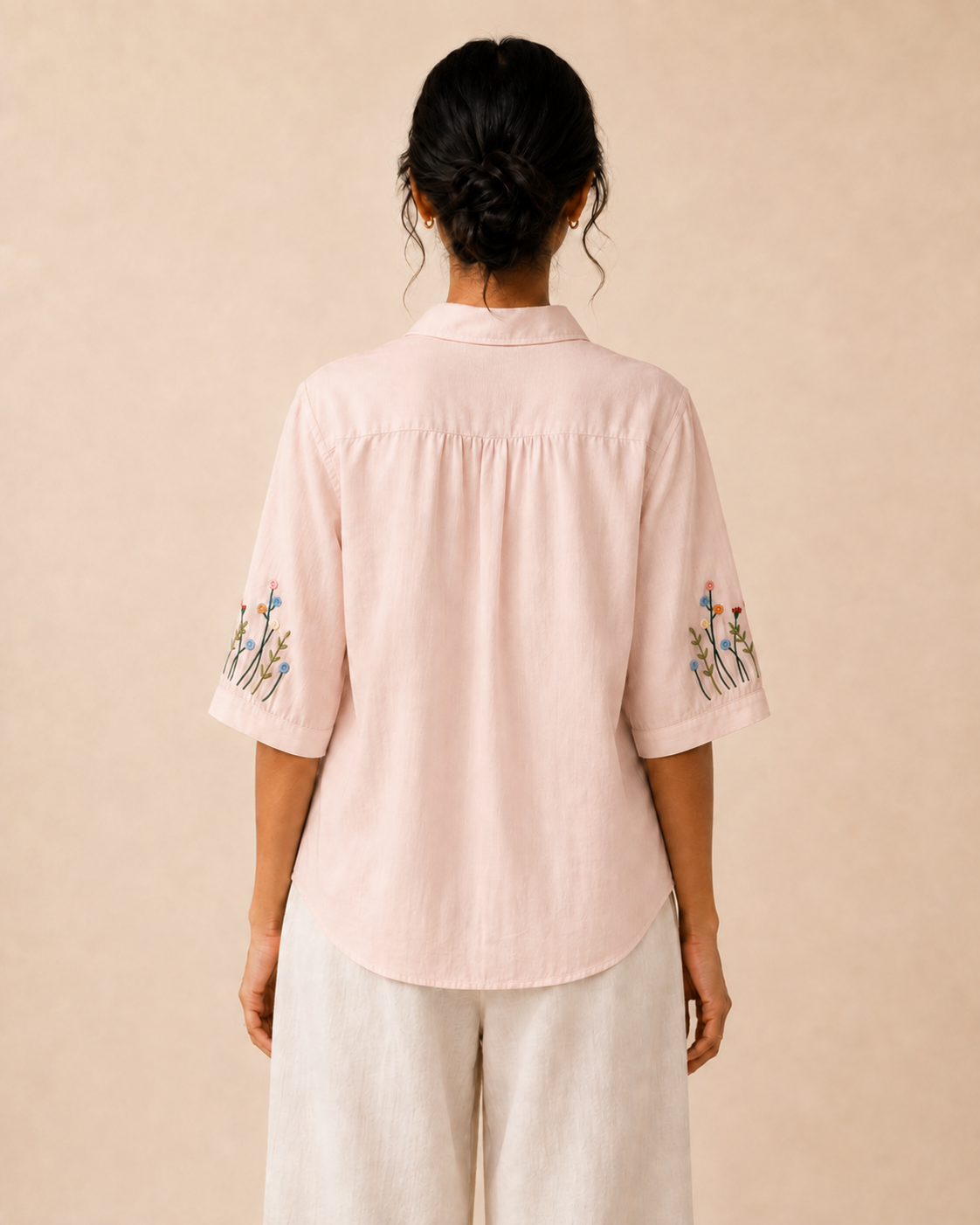 Back view of the soft blush pink wildflower embroidered cotton shirt, showing the rear yoke and relaxed fit.
