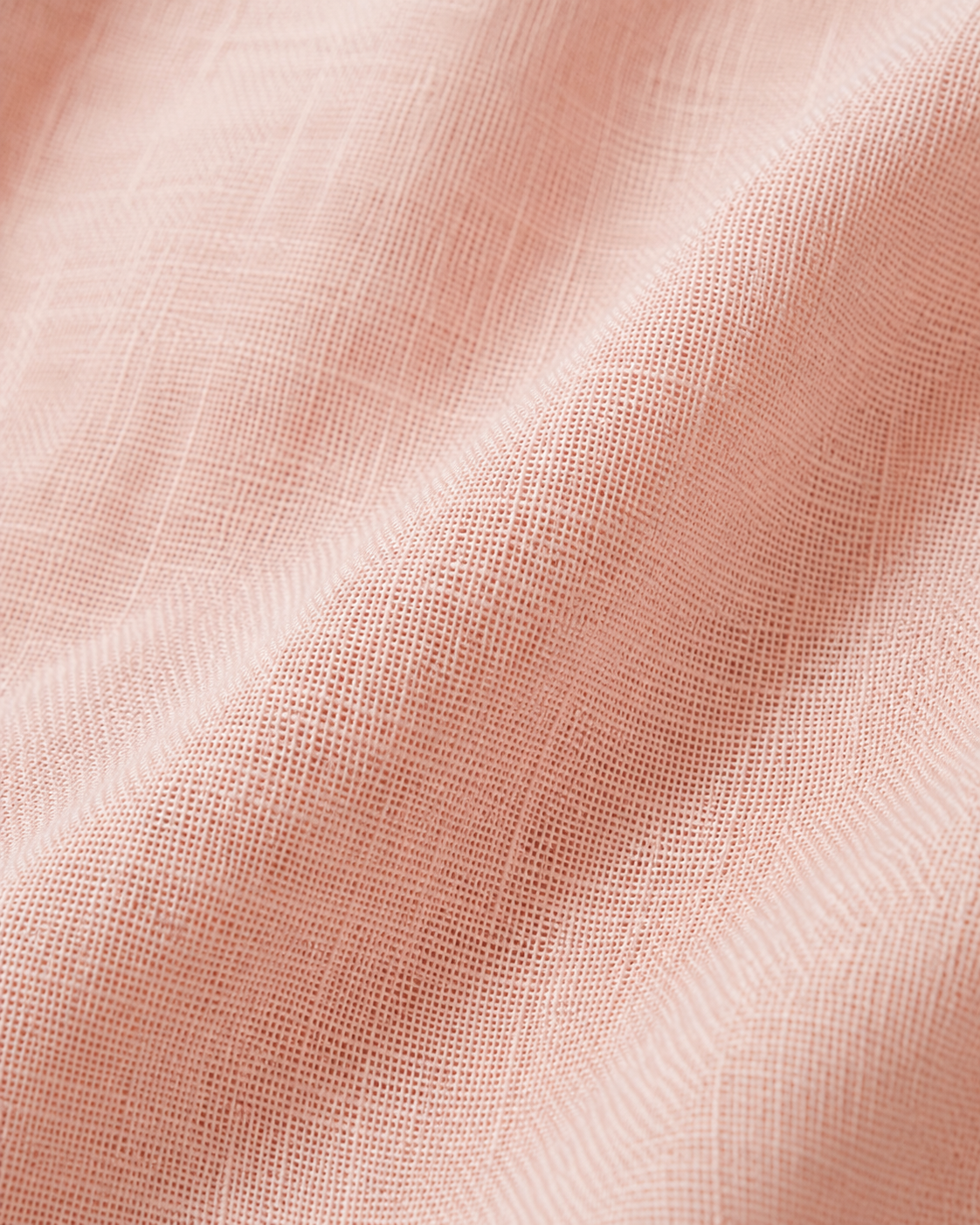 Close-up of the soft blush pink cotton fabric texture and soft folds.
