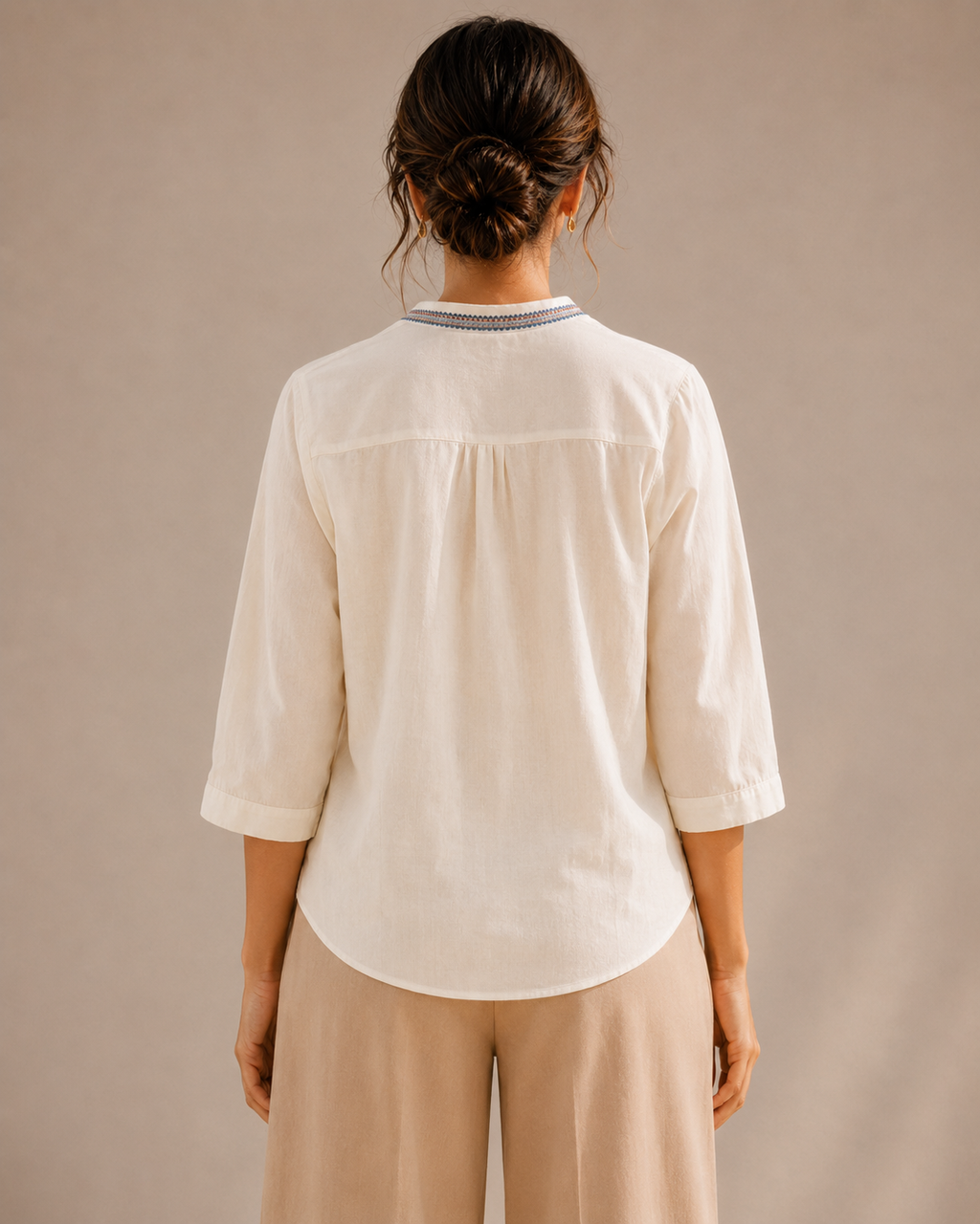 Back view of the untucked warm ivory white medallion embroidered cotton shirt, showing the curved hem and relaxed fit.

