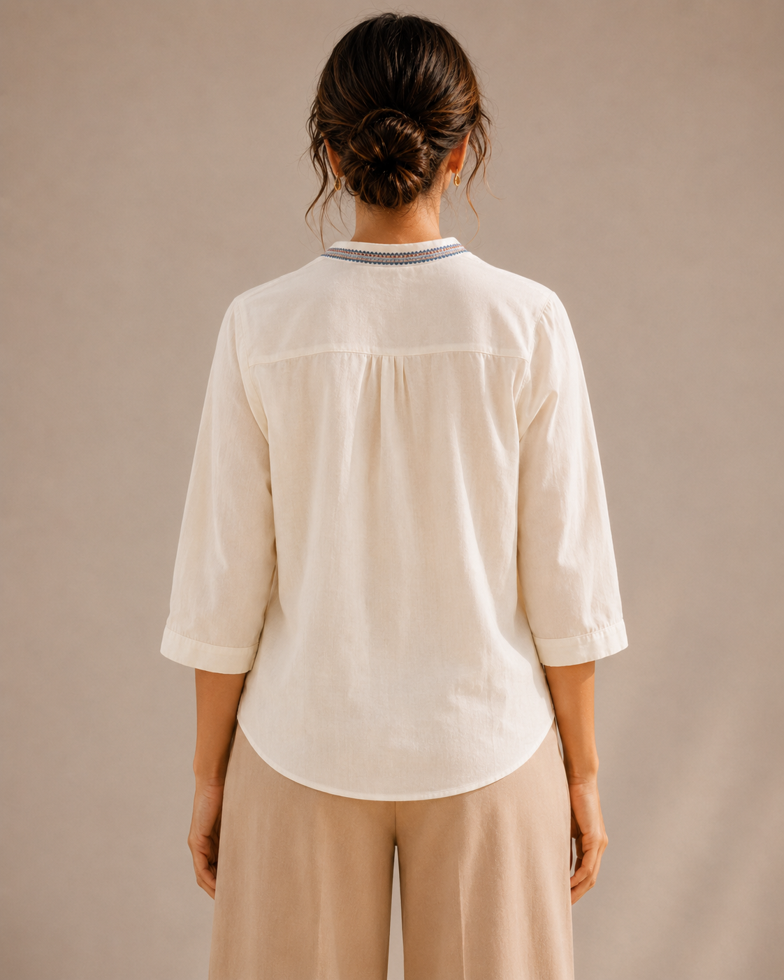 Back view of the untucked warm ivory white medallion embroidered cotton shirt, showing the curved hem and relaxed fit.
